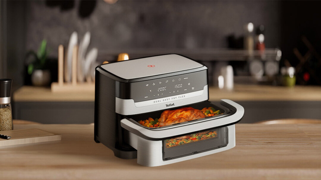 Frytkownica beztłuszczowa EY922D z otwartą szufladą – z kurczakiem i warzywami. W tle szafki kuchenne.