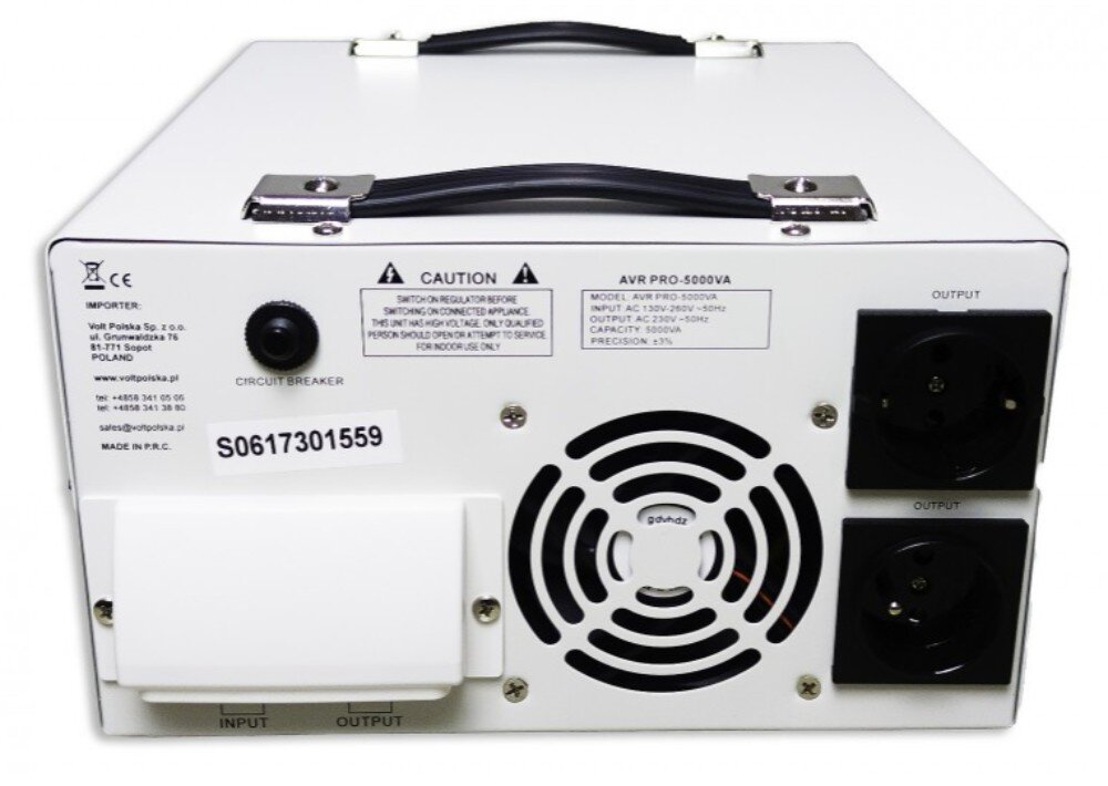 Stabilizator napięcia VOLT AVR Pro Tylny panel białej metalowej obudowy urządzenia z dwoma gniazdkami elektrycznymi po prawej stronie, okrągłym wywietrznikiem wentylatora pośrodku oraz bezpiecznikiem i osłoną złączy po lewej stronie, a także naklejkami informacyjnymi i dwoma czarnymi uchwytami na górze