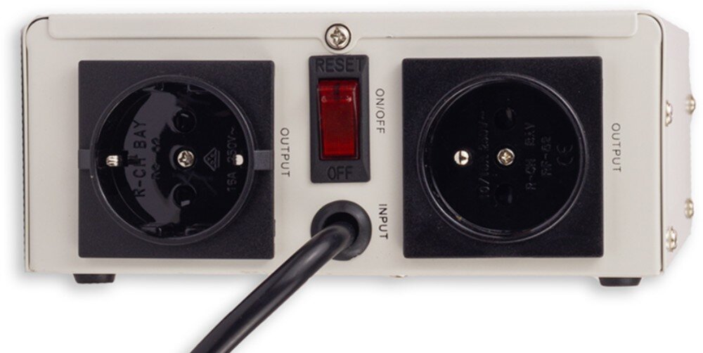 Stabilizator napięcia VOLT AVR Zbliżenie na boczny panel sterowania zawierający od lewej włącznik nadprądowy, gniazdo bezpiecznika, gniazdo sieciowe typu Schuko oraz czerwony przycisk zmiany trybu opóźnienia