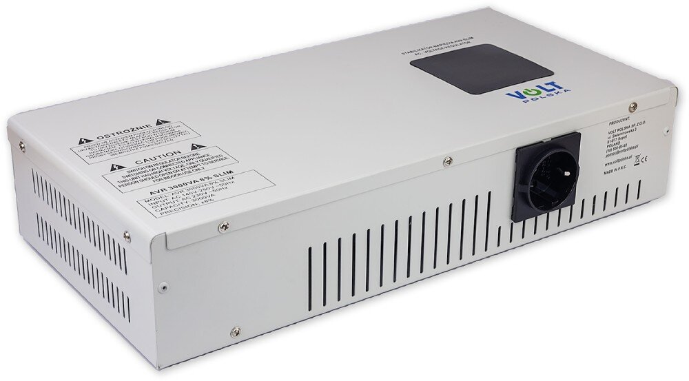 Stabilizator napięcia VOLT AVR Biała metalowa obudowa urządzenia elektronicznego widoczna z ukosa, prezentująca górny panel z czarnym ekranem i naklejkami ostrzegawczymi oraz bok z otworami wentylacyjnymi i gniazdem wyjściowym