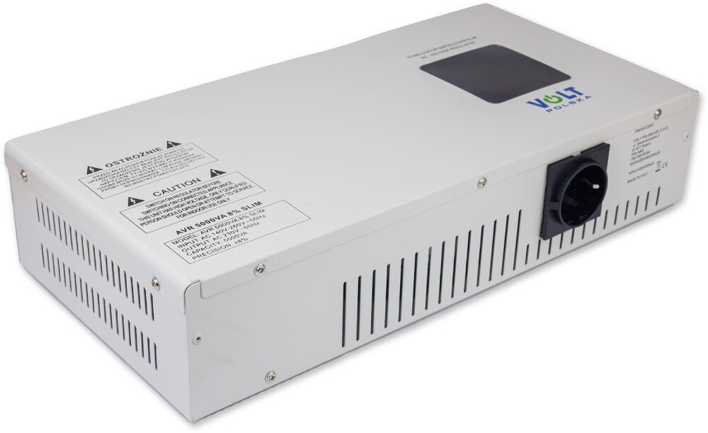 Stabilizator napięcia VOLT AVR Biała metalowa obudowa urządzenia elektronicznego widoczna z ukosa, prezentująca górny panel z czarnym ekranem i naklejkami ostrzegawczymi oraz bok z otworami wentylacyjnymi i gniazdem wyjściowym