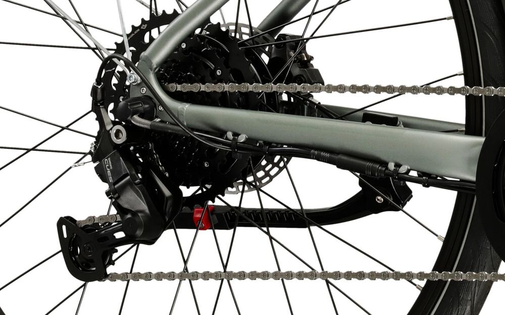 Zdjęcie przedstawia tylną część roweru z widocznym mechanizmem przerzutki i łańcuchem. Rower ma grafitowy kolor ramy i czarne elementy przerzutki.