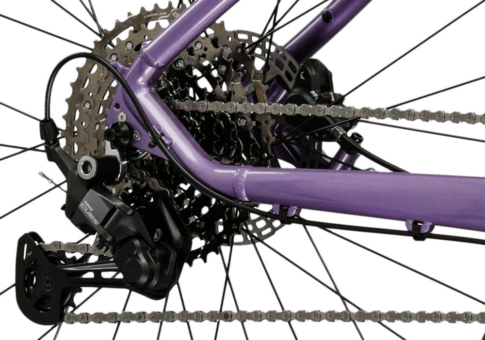 Rower górski MTB INDIANA X-Pulser 3.9 D18 29 cali damski Lawendowo-fioletowy zbliżenie na tylną przerzutkę przerzutki marki SHIMANO 10 przełożeń duża wytrzymałość sprawne działanie zmiana biegów jest płynna i bezproblemowa tylny napęd SHIMANO CUES U6000 precyzyjna praca mechanizmu komfort i kontrola