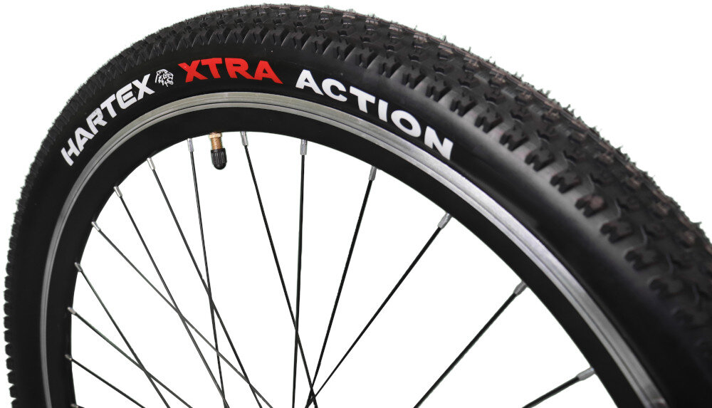Zdjęcie przedstawia oponę rowerową z widocznym napisem \'HARTEX XTRA ACTION\'. Opona ma wyraźny bieżnik i jest zamontowana na metalowej obręczy z szprychami.