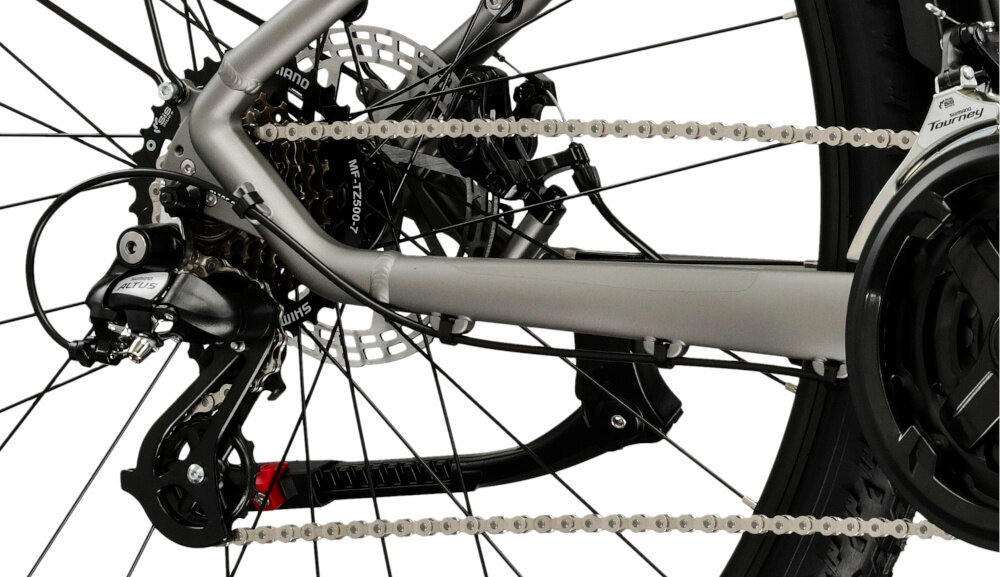 Rower górski MTB KROSS XPRT SUV M20 29 cali męski Srebrno-szampański zbliżenie na tylną przerzutkę białe tło widok z boku przerzutki marki SHIMANO 21 przełożeń duża wytrzymałość sprawne działanie zmiana biegów jest płynna i bezproblemowa przednie przerzutki SHIMANO Torney tylna przerzutka SHIMANO Altus technologia SHADOW przerzutka jest schowana i mniej narażona na uszkodzenia
