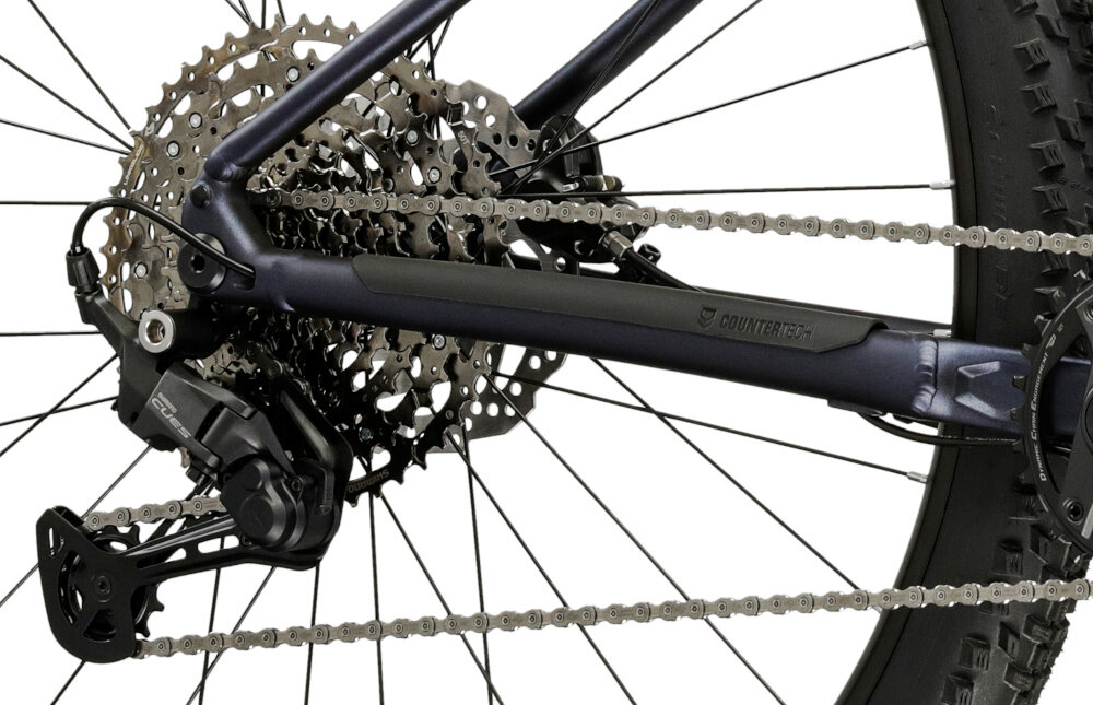 Zdjęcie przedstawia tylną część roweru górskiego z widocznym mechanizmem przerzutki i łańcuchem. Na ramie znajduje się napis \'COUNTERPUNCH\'.