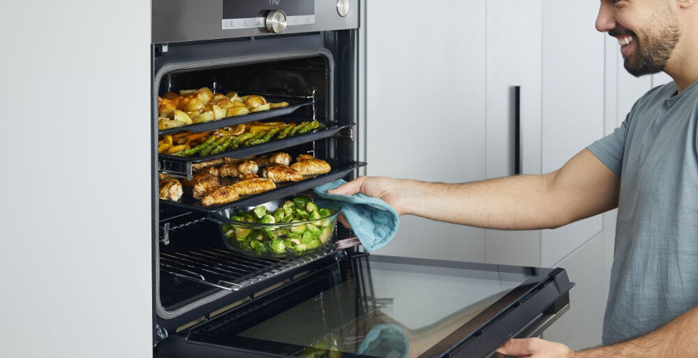 PIEKARNIK HISENSE BSA6633PBG8 wizualizacja mężczyzna otwarty piekarnik ręka wyciągająca naczynie danie blachy mięso warzywa ziemniaki pieczenie gotowanie wielopoziomowe 5 poziomów równoczesne pieczenie kilku dań wygodne łatwe