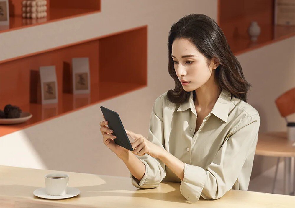 Czytnik e-booków ONYX BOOX Go Kobieta w jasnej koszuli siedząca przy stoliku w kawiarni, obsługująca czytnik dotykowy, bateria, automatyczne wyłączenie, funkcja uśpienia, ładowanie, port USB-C