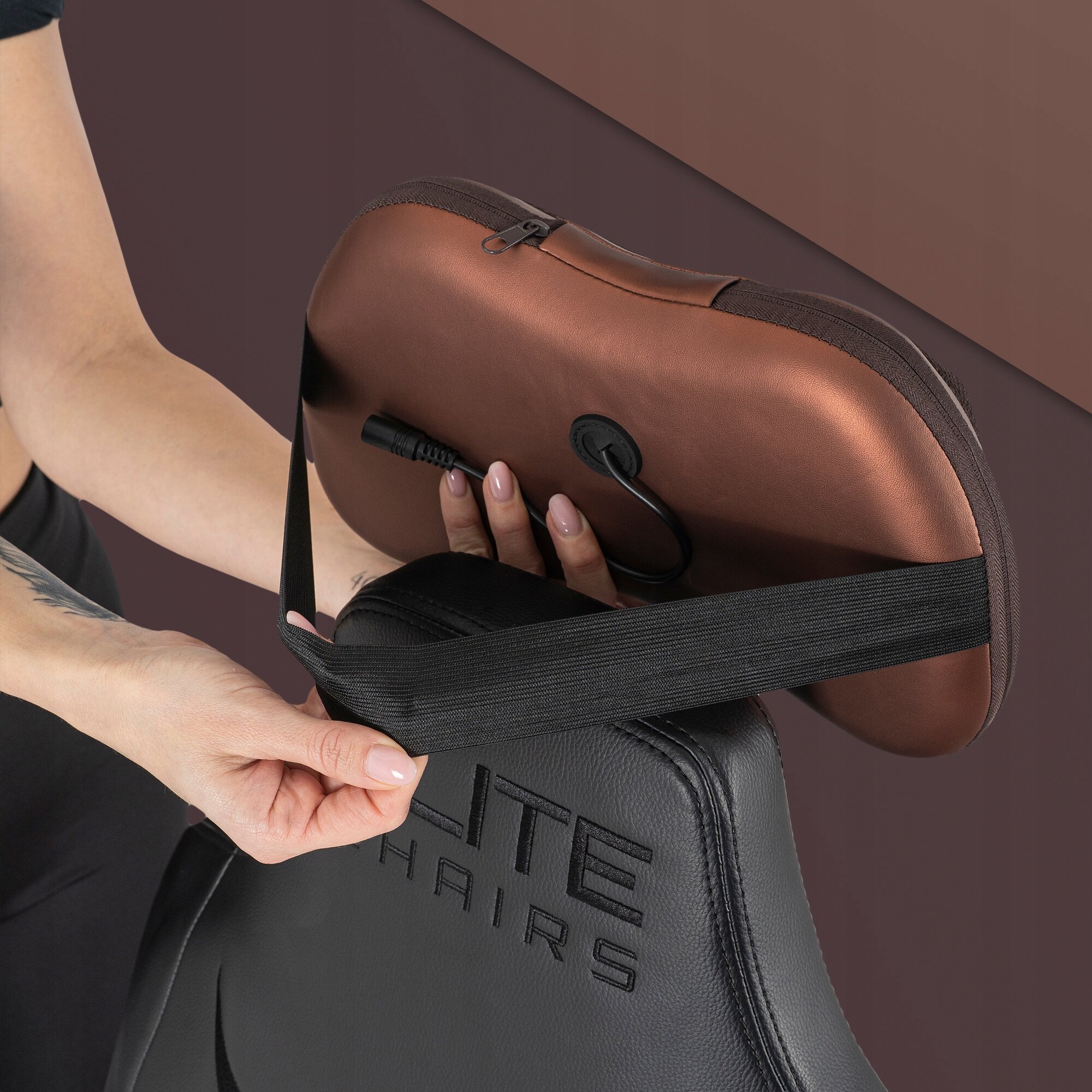 Osoba mocuje brązową poduszkę masującą z kablem do czarnego fotela z napisem \'ELITE CHAIRS\'.