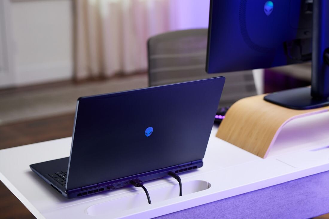 Laptop Dell Alienware 16 Aurora z portami na boku podłączony kablami na białym biurku w fioletowym oświetleniu - HDMI USB Type-C USB-A    
