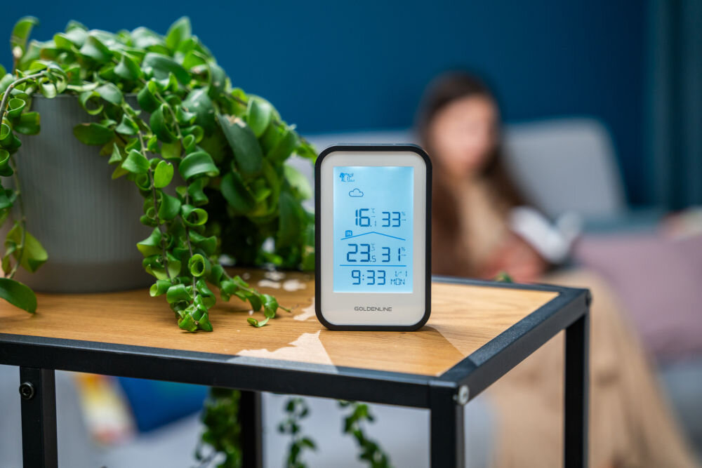 Stacja pogody GOLDENLINE GMS200 stojąca na blacie z podświetlonym na niebiesko wyświetlaczem temperatura wilgotność data godzina animacje