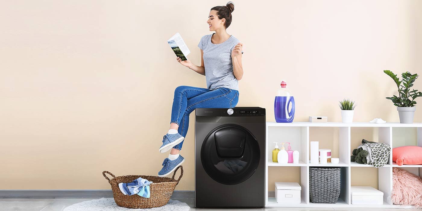 Kobieta siedzi na pralko - suszarce i czyta książkę Kobieta siedzi na pralko - suszarce i czyta książkę