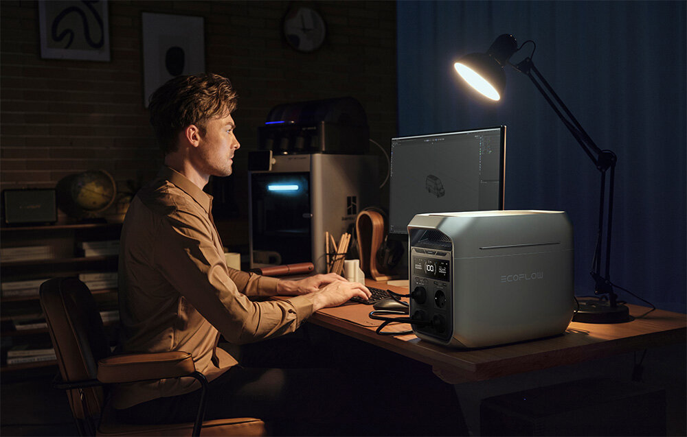 Przenośna stacja zasilania EcoFlow DELTA 3 Plus, Kompatybilny i wszechstronny, Mężczyzna pracuje przy biurku, stacja podpięta pod urządzenia biurowe