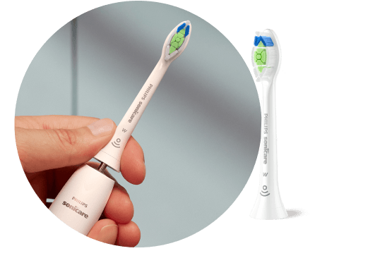 Dłoń trzymająca szczoteczkę z wyjętą końcówką. Obok znajduje się końcówka szczoteczki.