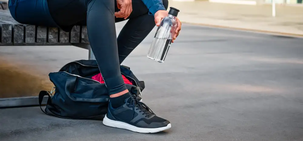 Mężczyzna ubrany na sportowo odkładający butelkę wody do torby