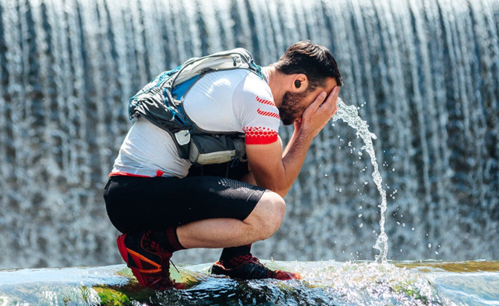 Słuchawki dokanałowe JBL Endurance Race 2 - aktywność w rytmie dźwięku, komfort i stabilność, osoba z założonymi słuchawkami dokanałowymi myjąca twarz wodą