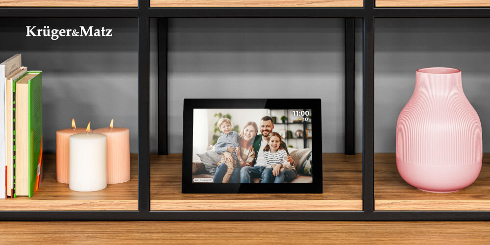 Ramka cyfrowa KRUGER&MATZ KM1100 Frameo 10.1 cala Czarny prezentacja ramki ze zdjęciem i komentarzem do niej od frontu na szafce w pokoju obok świeczki książki i różowy wazon