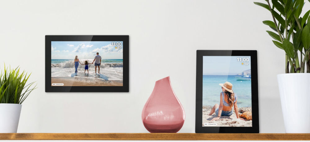 Ramka cyfrowa KRUGER&MATZ KM1100 Frameo 10.1 cala Czarny prezentacja ramki ze zdjęciem w dwóch opcjach montażu wisząca poziomo i stojąca pionowo obok kwiatki pomiędzy różowy wazon jasna ściana dostosowanie odpowiedniego miejsca