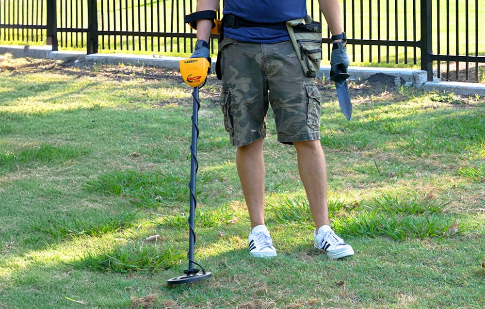 Wykrywacz metalu GARRETT ACE 250, Pinpoint, precyzyjne, monety, wykop, Mężczyzna na trawniku podczas poszukiwań z wykrywaczem Garrett.