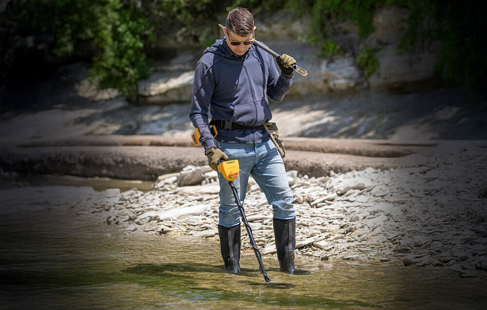 Wykrywacz metalu GARRETT ACE 150, Garrett ACE 150, wykrywacz, metale, skarby, Mężczyzna brodzi w wodzie z wykrywaczem metali Garrett ACE 150.