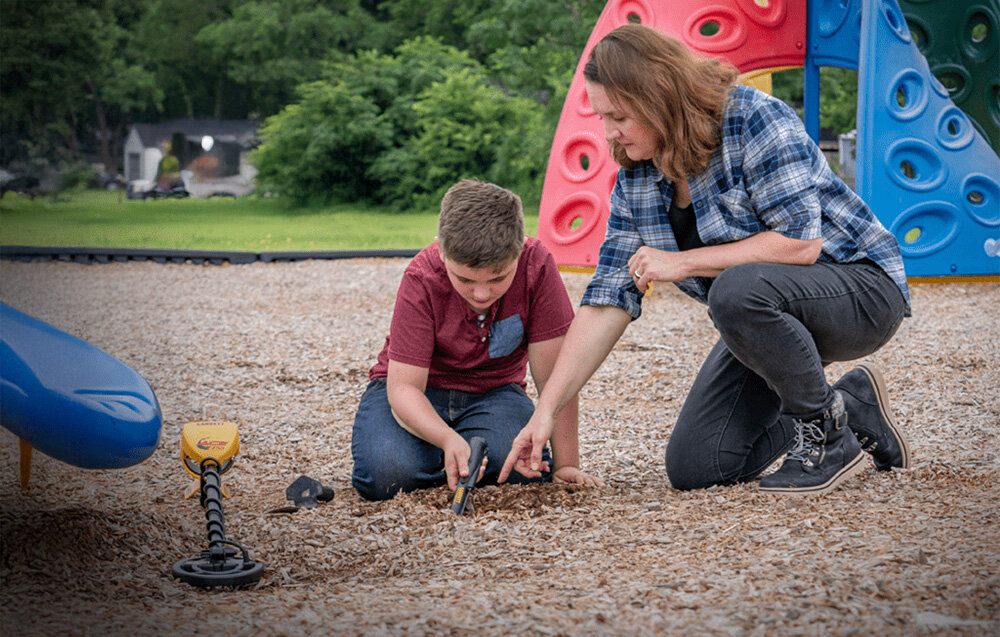 Wykrywacz metalu GARRETT ACE 150, monety, 5-15cm, wykop, złoto, Kobieta i dziecko szukają skarbów wykrywaczem na placu zabaw.