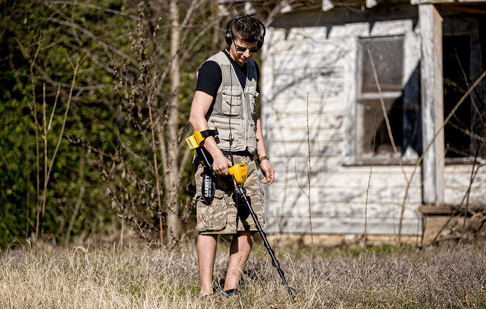 Wykrywacz metalu GARRETT ACE 300i, Garrett ACE 300i, wykrywacz, metale, skarby, Mężczyzna w słuchawkach szuka skarbów przy opuszczonym domu.