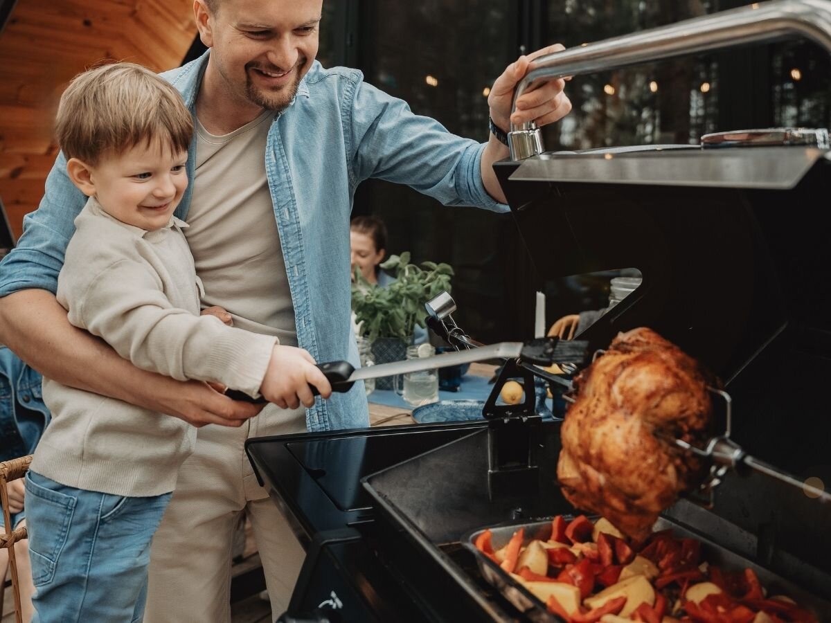 Rożen elektryczny BROIL KING 60522, rożen, grill, mięso, kulinaria, Tata z synem grillują kurczaka na obrotowym rożnie.