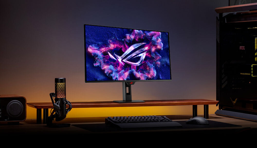 Monitor ASUS ROG Strix XG27ACDMS 26.5 cali 2560x1440px 280Hz 0.03 ms [GTG] Monitor z wyświetlonym dynamicznym logo ustawiony na biurku w ciemnym pomieszczeniu z jasnym podświetleniem obok komputer