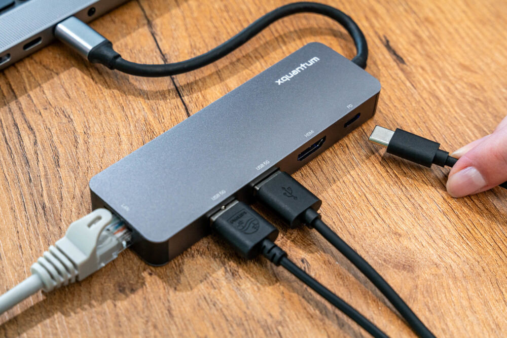 Hub USB XQUANTUM UH220 5w1 hub podpięty do komputera obok wtyczki ułożone obok portów adaptera