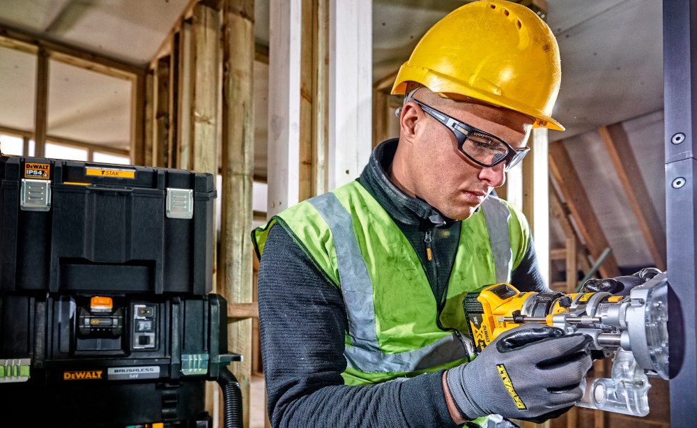 Skrzynka narzędziowa DEWALT DWST83346-1 plac budowy skrzynka ustawiona na innych skrzynkach na pierwszym planie pracuje osoba obudowa z tworzywa sztucznego odporna na uszkodzenia mechaniczne i działanie czynników zewnętrznych metalowe zatrzaski i metalowe zawiasy udźwig do 30 kg