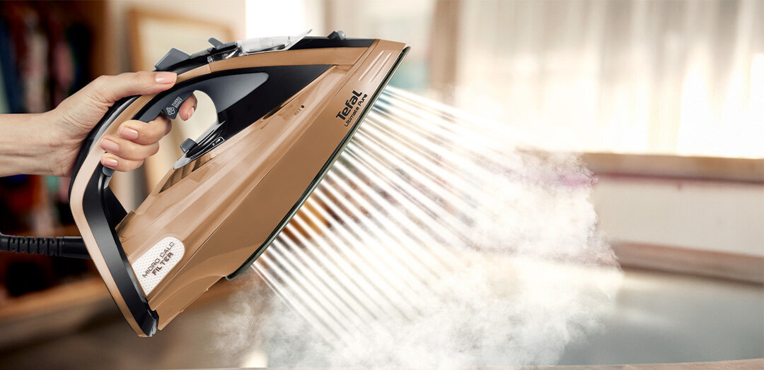 Żelazko trzymane w ręce. Z urządzenia wydobywa się mocny strumień pary.