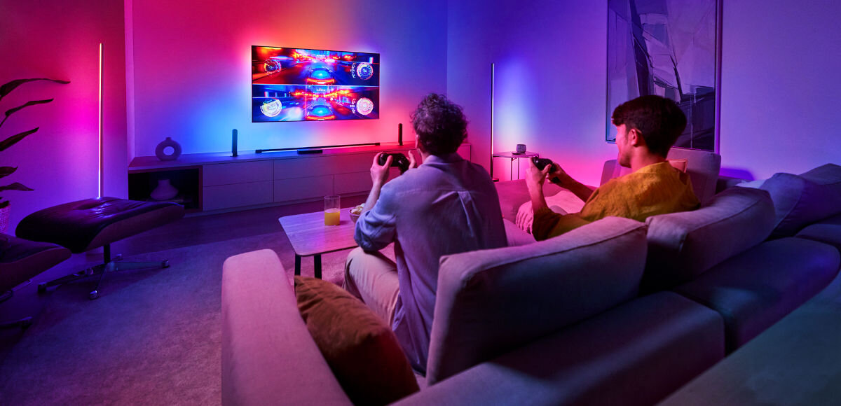 Centralka PHILIPS HUE 929003499601, synchronizacja, Philips hue, reagowanie, światło, 2 osoby siedzą na sofie, grając w grę na tv