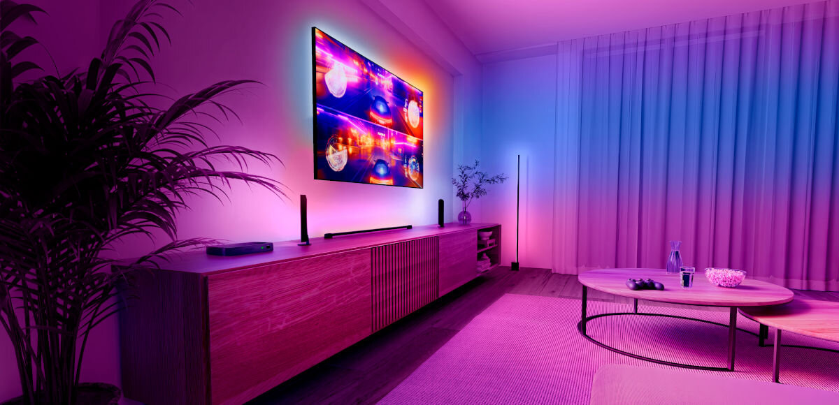 Centralka PHILIPS HUE 929003499601, telewizor w różnych barwach na ekranie i animacji, w tle pomieszczenie pokoju gościnnego