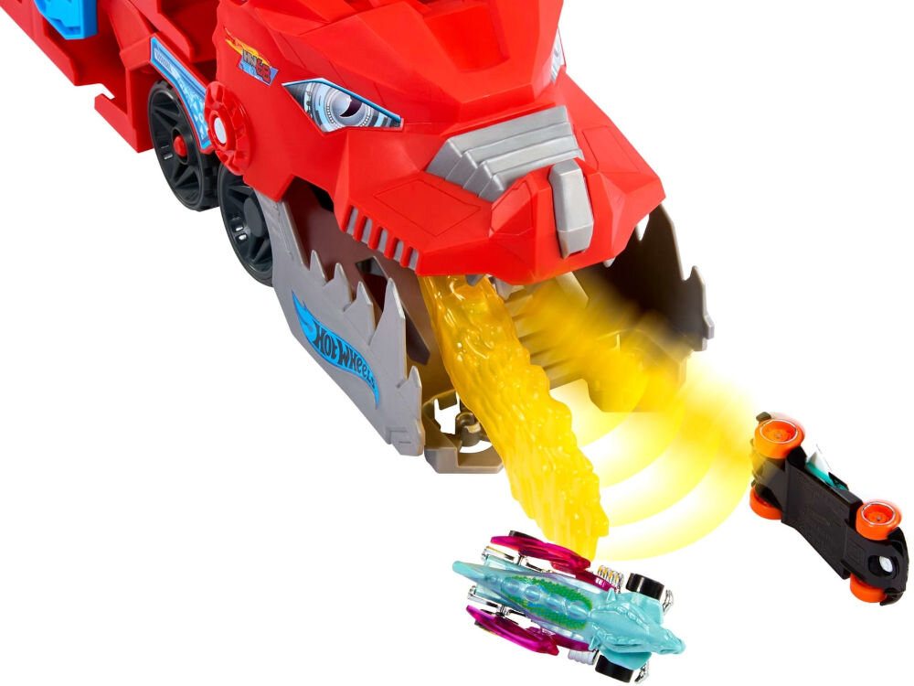 Zestaw pojazdów Hot Wheels City Transporter podwójny smok JBM72 Duży czerwony pojazd Hot Wheels w kształcie smoka wypluwa żółty, świetlisty ogień, z którego wyłaniają się dwa małe samochodziki Hot Wheels.
