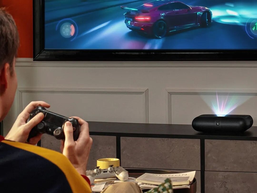 Projektor YABER K300s - Cichy, oszczędny i trwały, żywotność lasera, projektor stojący na komodzie wyświetlający obraz na ścianie, osoba grająca w grę