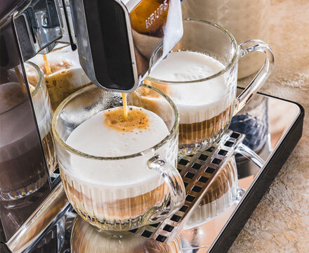 Ekspres do kawy KRUPS Intuition Experience Hot&Cold EA879N przygotowujący dwie kawy mleczne w szklanych filiżankach.