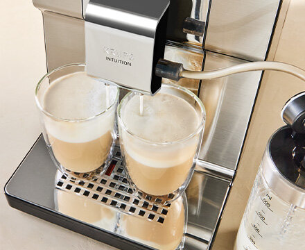 Ekspres do kawy KRUPS Intuition Experience Hot&Cold przygotowujący dwie kawy mleczne w szklankach, widoczna pianka.