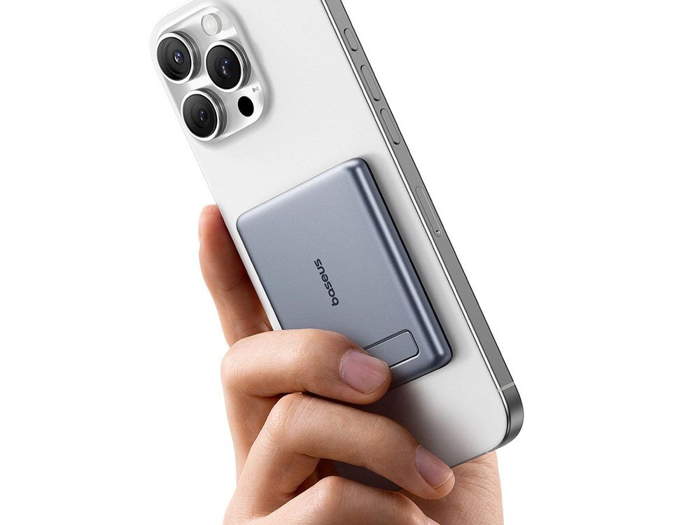 Szary powerbank Baseus z rozłożoną podstawką przyczepiony do białego iPhone'a trzymanego pionowo w dłoni.
