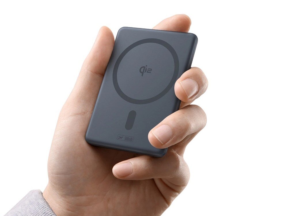 Szary powerbank Baseus z oznaczeniem Qi2 i pierścieniem magnetycznym trzymany w dłoni na białym tle.