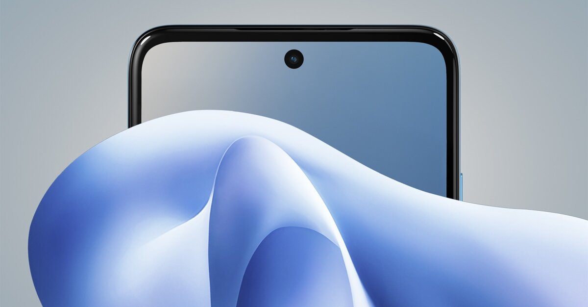 Widoczna jest górna część smartfona z ekranem i centralnie umieszczoną kamerą przednią. Na pierwszym planie znajduje się abstrakcyjny, niebieski kształt.