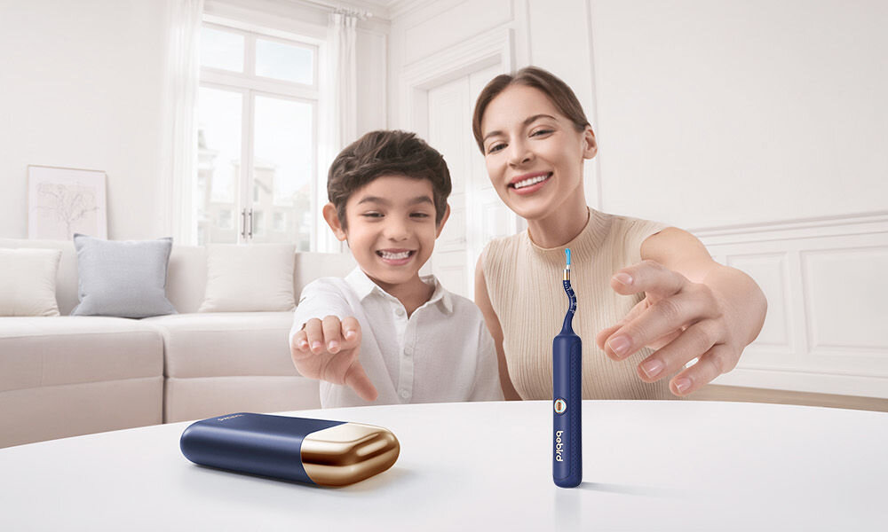 Otoskop do uszu z kamerą BEBIRD Earvision Plus I35R na stole oczyszczacz i etui w tle dwie uśmiechnięte osoby