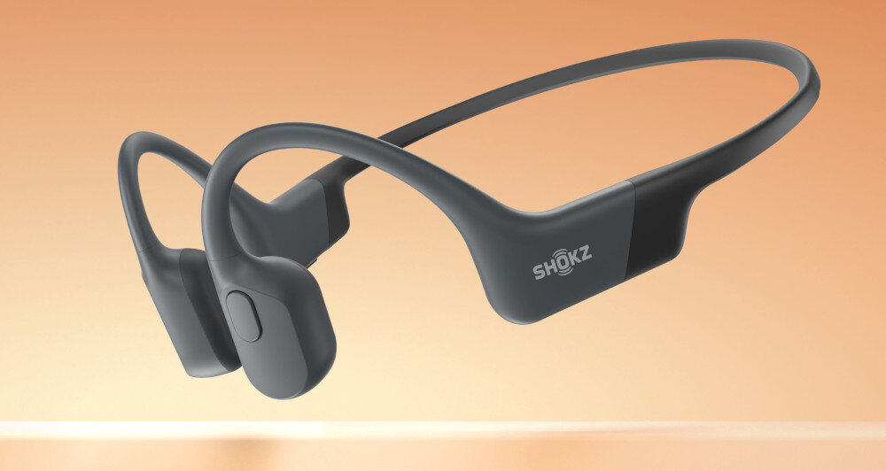 Słuchawki Shokz OpenRun - sluchawki na pomaraczowym tle, rozmowy, halas, otoczenie