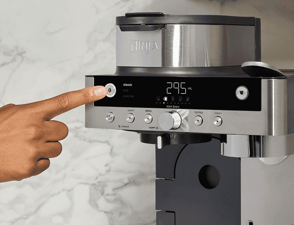 Osoba naciska przycisk na panelu sterowania ekspresu Ninja CFN803EU, na którym widnieje cyfrowy wyświetlacz