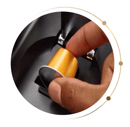 Zbliżenie na dłoń wkładającą złotą kapsułkę do gniazda w ekspresie Ninja CFN803EU