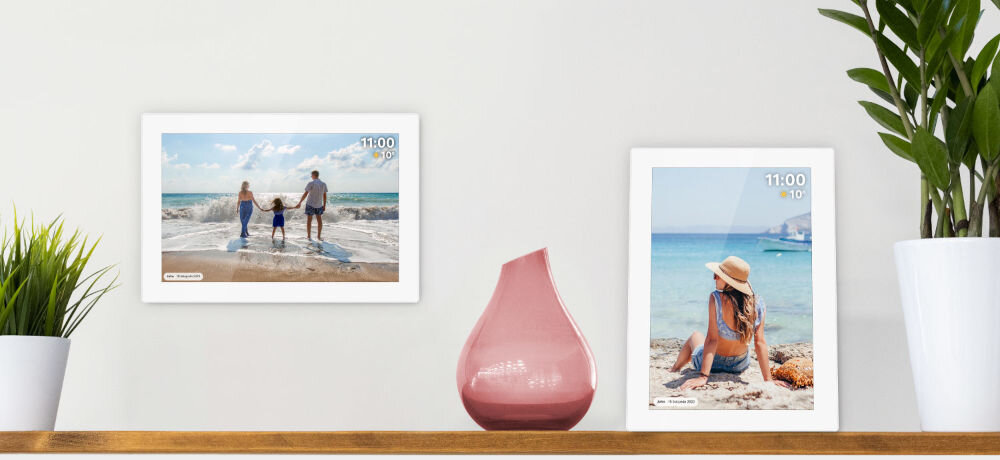 Ramka cyfrowa KRUGER&MATZ KM1100W Frameo 10.1 cala Biały prezentacja ramki ze zdjęciem w dwóch opcjach montażu wisząca poziomo i stojąca pionowo obok kwiatki pomiędzy różowy wazon jasna ściana dostosowanie odpowiedniego miejsca