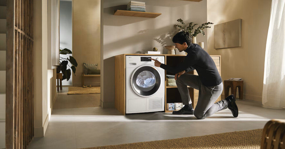 Suszarka MIELE TWD640WP EcoSpeed zdjęcie wizualizacyjne lifestyle pomieszczenie mężczyzna zmiana ustawień panel Optymalna ochrona domu optymalne wartości szczelności ochrona domu mebli pomieszczeń