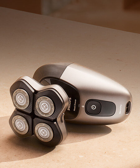 Golarka do głowy z czterema okrągłymi głowicami tnącymi, obudowa w kolorze srebrnym z czarnymi elementami. Na obudowie widoczne logo \'Philips\' oraz przycisk zasilania.
