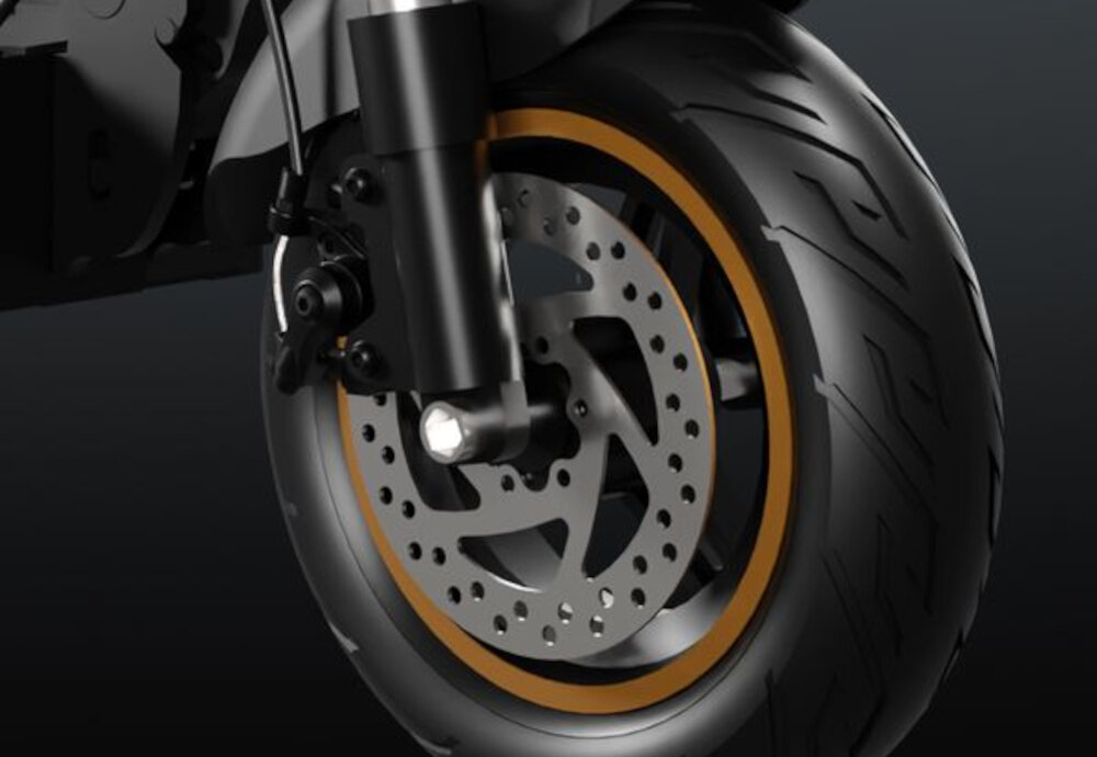 Hulajnoga elektryczna RUPTOR R1 V2 80 km 500W Amortyzacja 10 cali Miedziany ciemne tło zbliżenie na koło i przedni hamulec bezpieczeństwo przedni hamulec tylny mechaniczny hamulec tarczowy duża siła hamowania kierunkowskazy informują innych uczestników ruchu o zmianie kierunku jazdy