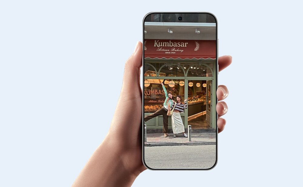 Telefon w dłoni, na wyświetlaczu film z dwoma kobietami na tle piekarni