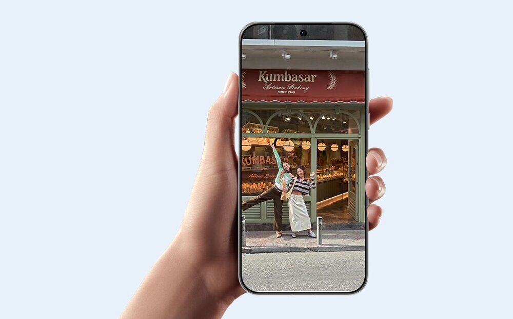 Telefon w dłoni, na wyświetlaczu film z dwoma kobietami na tle piekarni